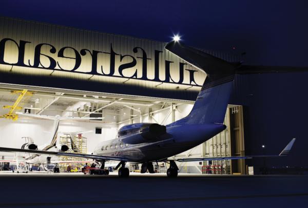 湾流服务中心外的夜晚. Plane entering hangar.